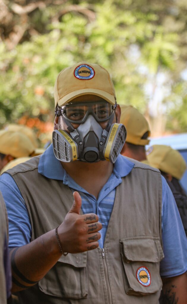 Un senepero posa con su uniforme y una mascara de protección. Levanta el pulgar en señal de aprobación